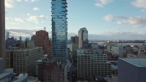 Landing-footage-in-city.-Modern-glass-facade-of-tall-Jenga-building-reflecting-sky.-Manhattan,-New-York-City,-USA