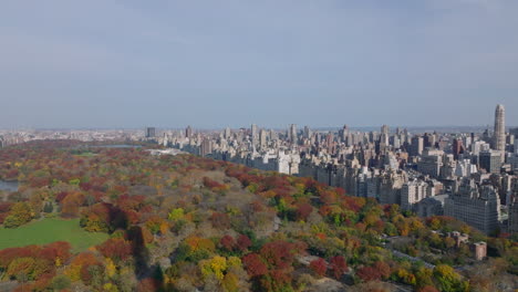 Aerial-panoramic-footage-of-large-park-with-autumn-colour-trees-and-surrounding-buildings.-Neighbourhoods-around-Central-park.-Manhattan,-New-York-City,-USA