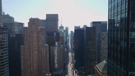 Forwards-fly-high-above-wide-street-sandwiched-between-tall-office-or-apartment-downtown-buildings.-Manhattan,-New-York-City,-USA