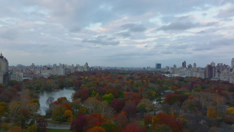Fly-above-amazing-colourful-trees-in-Central-park-in-autumn.-Large-urban-park-with-lake-and-walkways.-Manhattan,-New-York-City,-USA