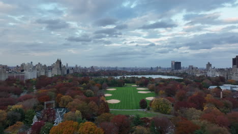 Forwards-fly-above-Central-park.-The-Great-Lawn-with-baseball-field-and-Jacqueline-Kennedy-Onassis-Reservoir-surrounded-by-autumn-colour-trees.-Manhattan,-New-York-City,-USA