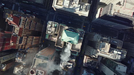 Aerial-birds-eye-overhead-top-down-ascending-shot-of-smoking-chimney-on-roof-of-historic-buildings-in-town-development.-Manhattan,-New-York-City,-USA