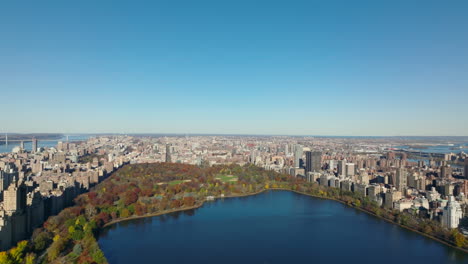 Idyllic-autumn-day.-Aerial-view-of-colourful-Central-Park-with-water-reservoir-and-buildings-in-town-around.-Clear-blue-sky.-Manhattan,-New-York-City,-USA