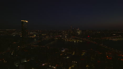 Aerial-panoramic-footage-of-Manhattan-and-Brooklyn-bridge-at-night.-Heavy-traffic-in-streets.-Manhattan,-New-York-City,-USA