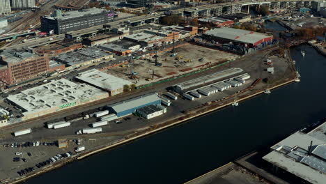 Aerial-view-logistic-site-on-waterfront.-Tilt-up-reveal-of-busy-highway-and-building-in-town.-Queens,-New-York-City,-USA