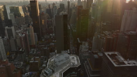 High-angle-view-of-high-rise-buildings-in-midtown.-Tilt-up-reveal-cityscape-against-sun.-Manhattan,-New-York-City,-USA